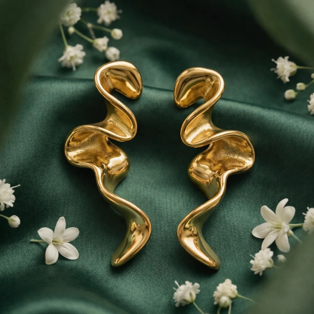 Sculptural gold earrings on green silk